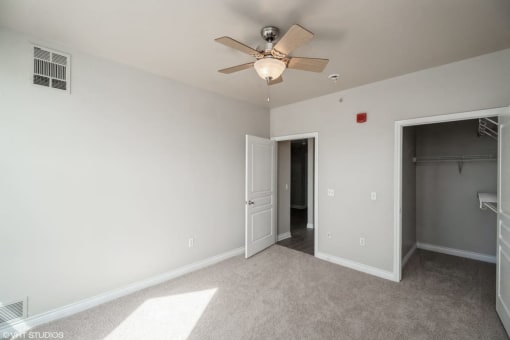 a bedroom with a ceiling fan and a door to a closet