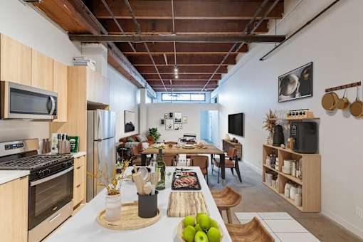 A kitchen with a wooden table and chairs, a refrigerator, a stove, a microwave, and a TV.