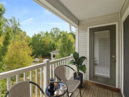 A table with a cup and a plant on a porch.