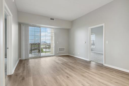 A spacious room with wooden flooring and a view of the city through the window.