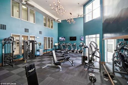 A gym with a variety of equipment including treadmills, weights, and exercise machines.