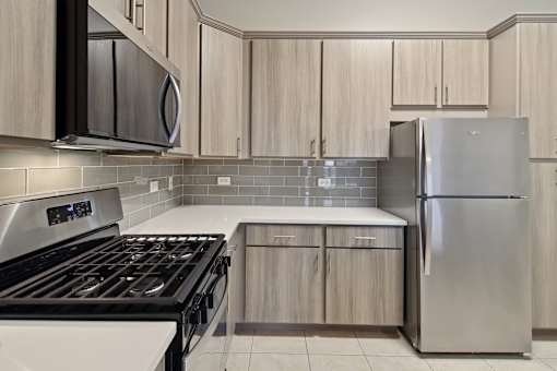 A modern kitchen with a stove, microwave, and refrigerator.
