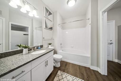 A bathroom with a white tub, sink, and toilet.