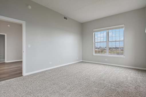 A spacious room with a large window and carpeted floor.