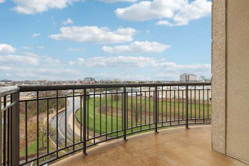 A balcony with a metal railing overlooks a baseball field.
