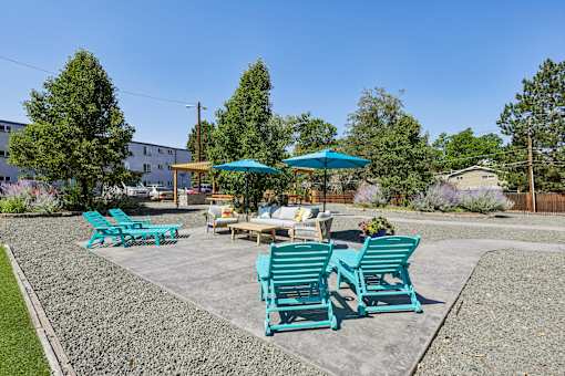 A sunny day at a park with blue chairs and a table.