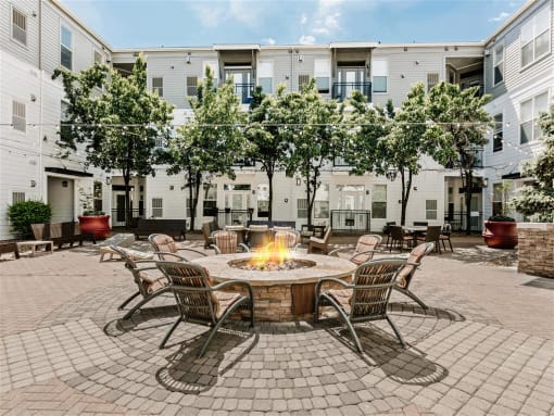 a fire pit in the middle of a patio with chairs and tables