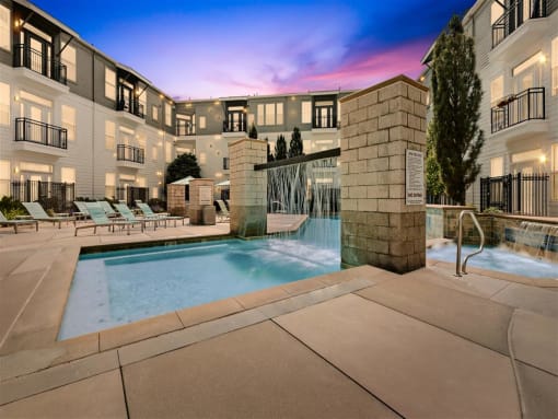 a swimming pool with a fountain in front of an apartment building