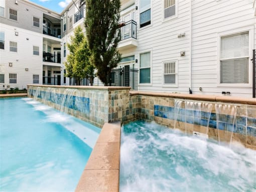 a pool with a waterfall in front of a building