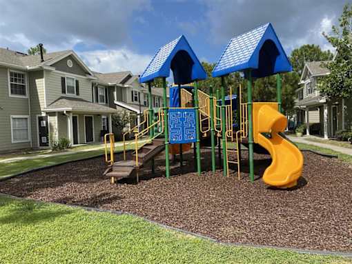A playground with a yellow slide and blue canopies.