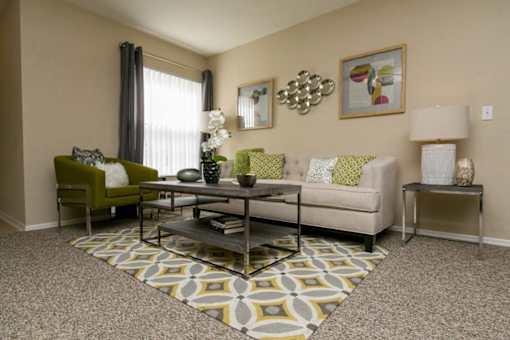 A living room with a green chair, a white couch, and a coffee table.