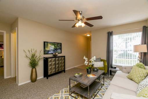 A living room with a white couch, a coffee table, and a ceiling fan.