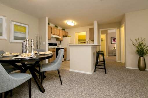 A dining table with two grey chairs and a carpet in a room.