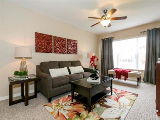 A living room with a brown couch, a coffee table, and a ceiling fan.