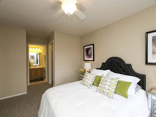 A bedroom with a bed, nightstand, and a ceiling fan.