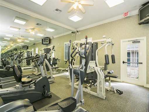 A gym with a variety of equipment including treadmills, weights, and a television.