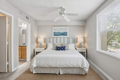 A bedroom with a white bed and a ceiling fan.