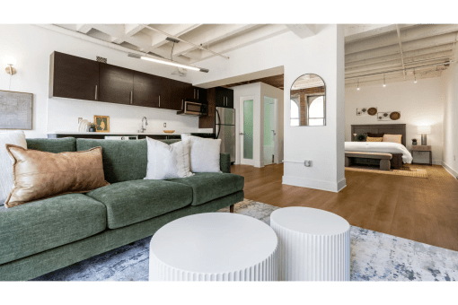 a living room with a green couch and two white stools