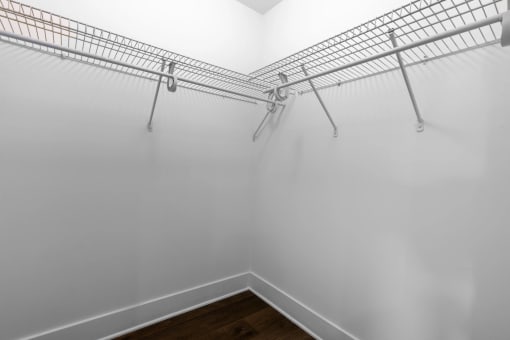 the closet in a bedroom with white walls and metal shelves