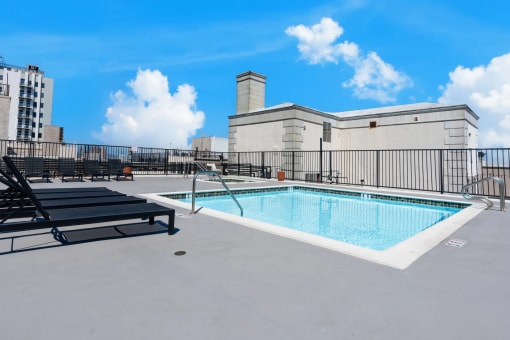 the pool on the rooftop of a building with chairs and a fence