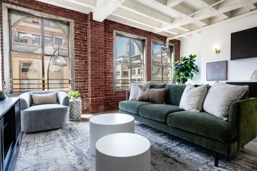 a living room with a green couch and a brick wall