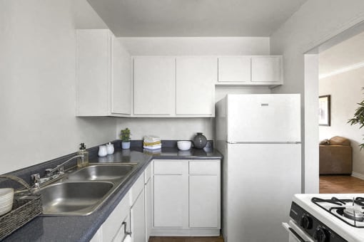 a white kitchen with a sink and a refrigerator