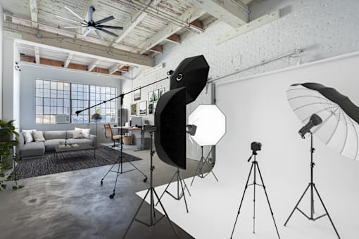 A photography studio with a ceiling fan, lighting equipment, and a couch.