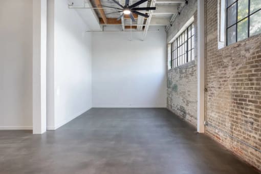 an empty room with a brick wall and a cement floor