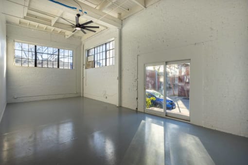 a large empty room with windows and a ceiling fan
