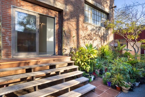 the front of a brick house with a large wooden porch and potted plants