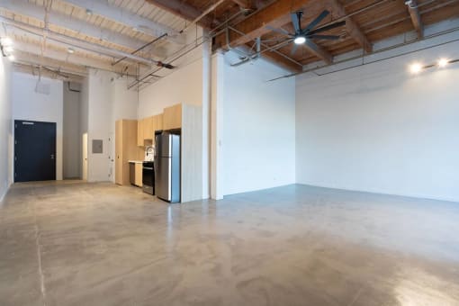an empty room with a refrigerator in the middle of it