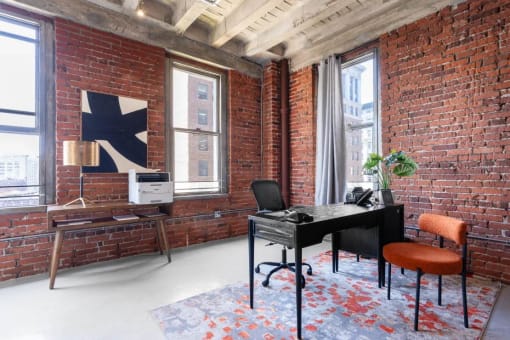 an exposed brick wall in a room with a desk and a chair