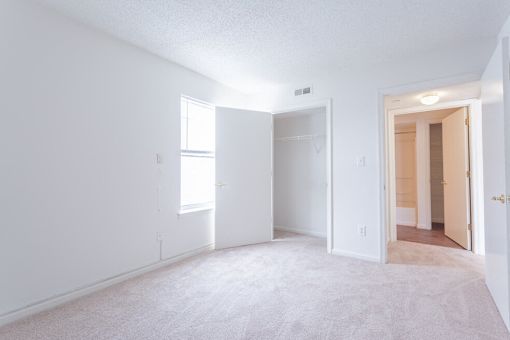 A white room with a carpeted floor and a door on the right side.