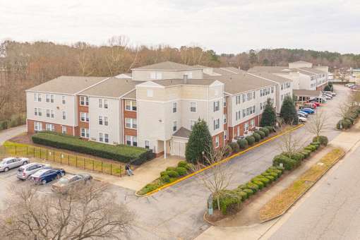 Apartment complex with a parking lot in front.