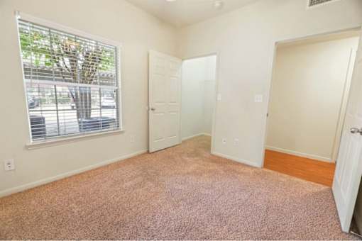 Bedroom with a large window and plush carpeting at  Stonehaven Apartments in Houston, TX