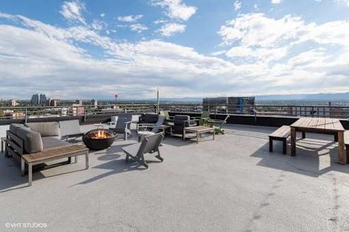 Rooftop patio with a fire pit and seating area at Archer Tower in Denver, CO