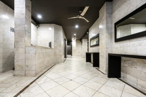 a large marble hallway in a public restroom with a ceiling fan