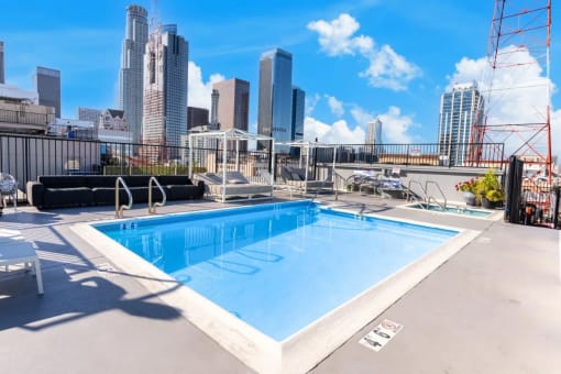 the pool on the roof of a building with a city in the background