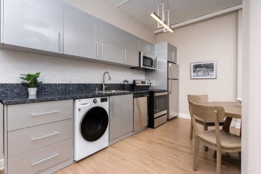 a kitchen with a washing machine and a table with a chair