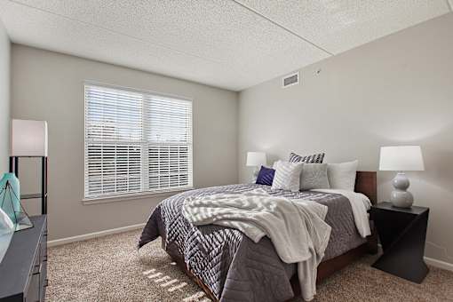 A bedroom with a bed, nightstand, and window.