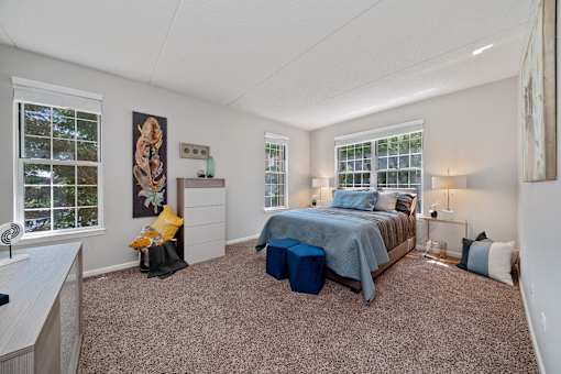 A bedroom with a bed, nightstand, and window.