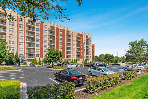 A parking lot in front of a large apartment building.