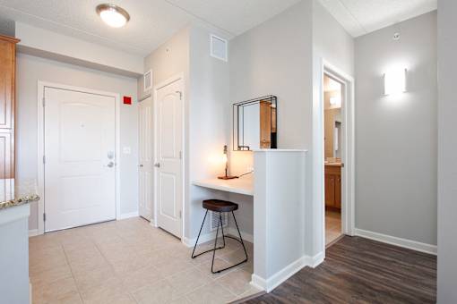 A room with a white door, a table with a black frame and a brown stool.