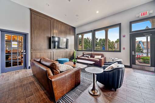 A living room with a brown couch and a television on the wall.