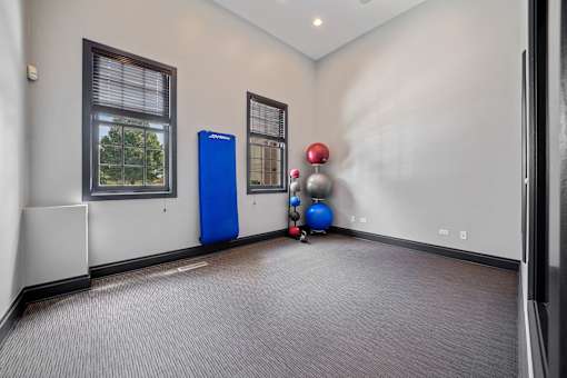 A room with a blue exercise machine and a red ball.