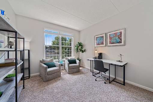 A room with a desk, chairs, and a window.