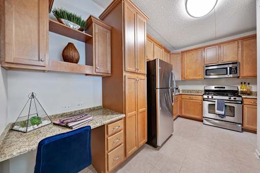 A kitchen with wooden cabinets and a blue chair.