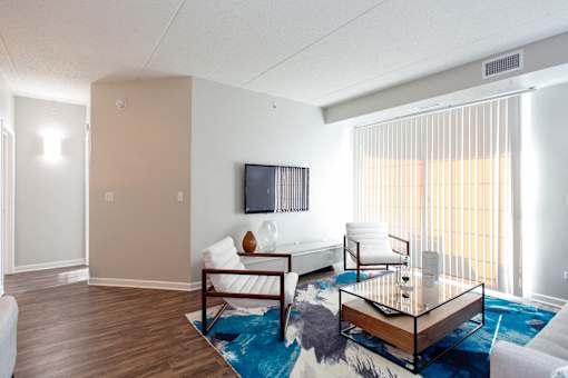 A living room with a white couch, a wooden coffee table, and a flat screen TV mounted on the wall.