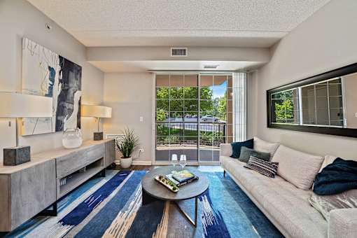 A living room with a couch, a coffee table, and a large window.