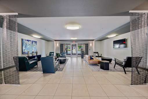 A spacious waiting area with a variety of seating options and a television mounted on the wall.